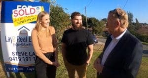 Picture of buyers standing in front of a for sale - sold sign on a property in bayswater WA