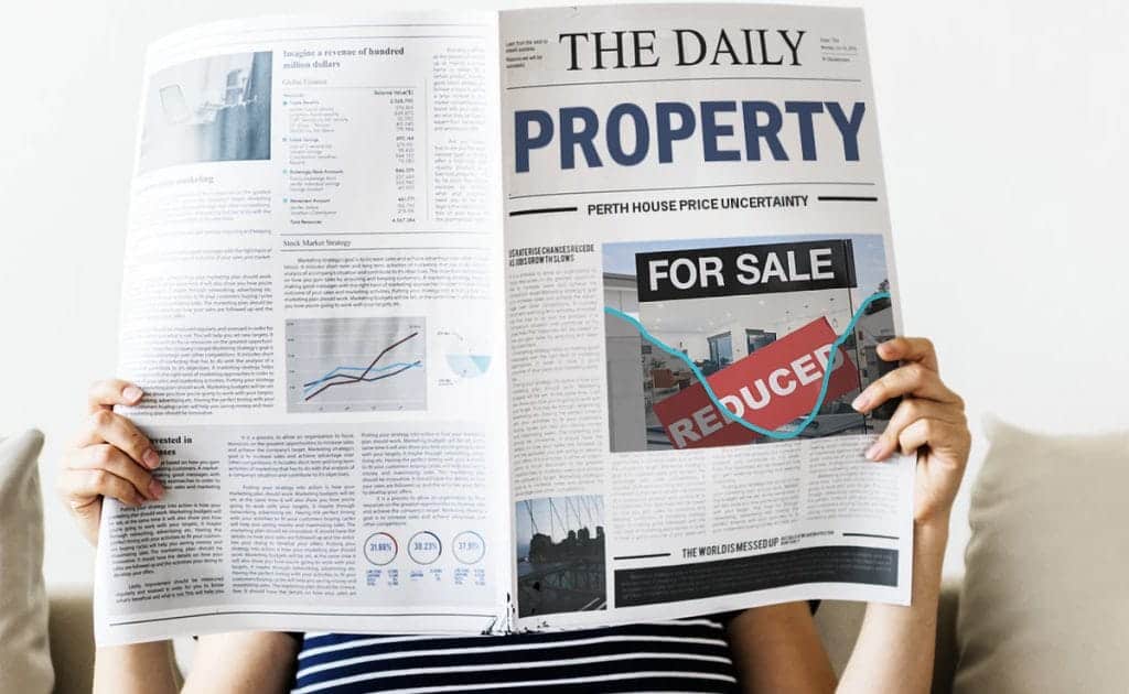 Woman reads the newspaper with headlines about the uncertainty of the property market during covid-19.