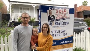 Happy Bayswater Home sellers in front of Sold sign