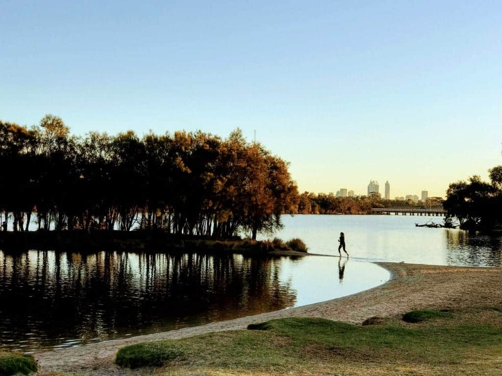 A child is reflected in the water of the Swan River in Bayswater