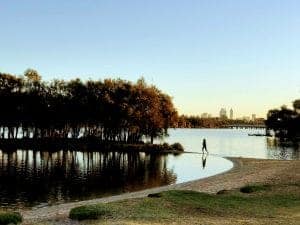 A child is reflected in the water of the Swan River in Bayswater